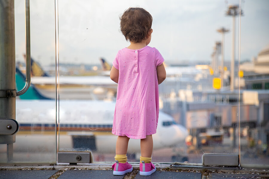 A toddler stands at the airport looking down at airplanes below. How to get a US Passport and Social Security Number for your child born abroad.