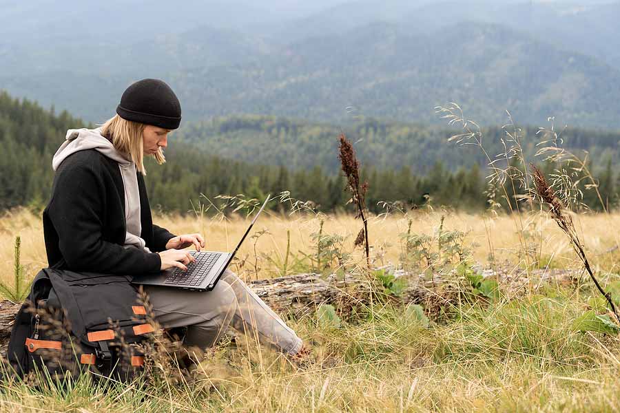 A woman reading "23 things to know about US expat taxes in 2023" as she sits in the forest.