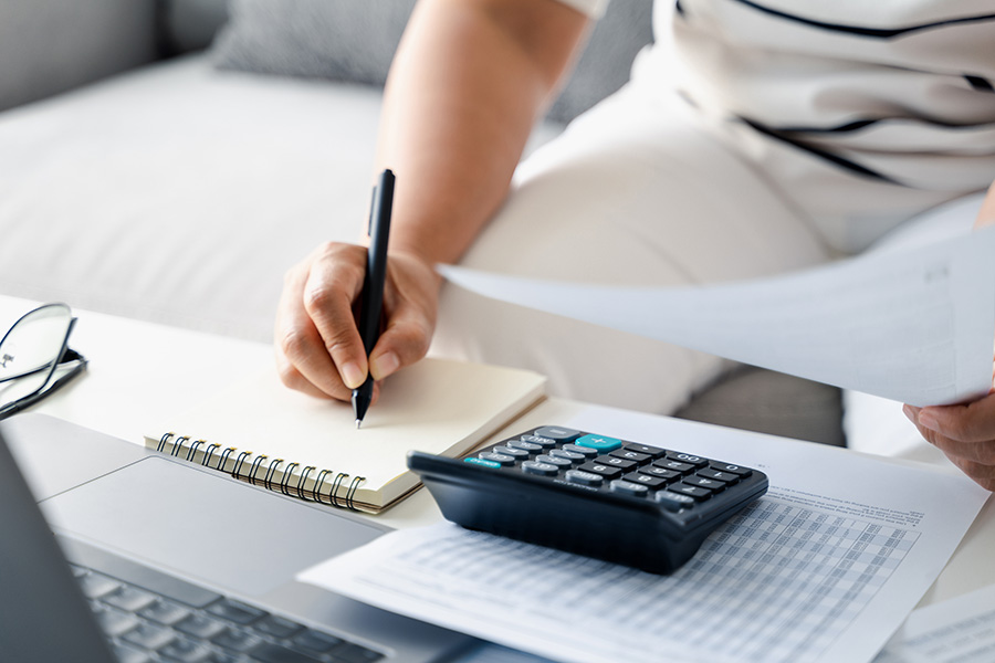 A person using a notebook and calculator to figure out 