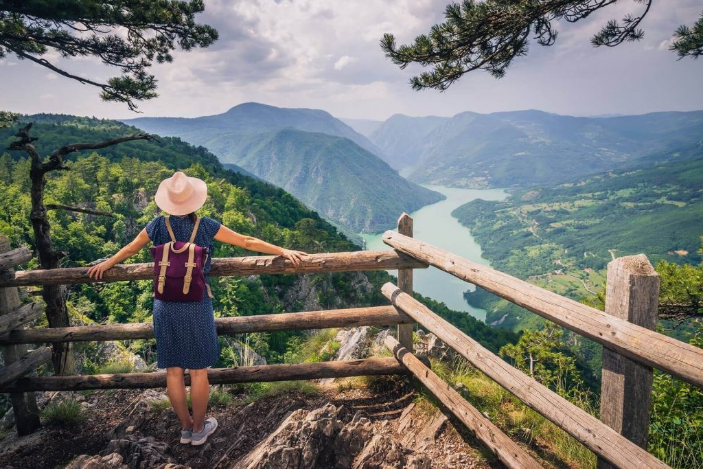 Woman hiking in the mountains on a beautiful summer day, not quite worrying about filing us taxes from abroad.