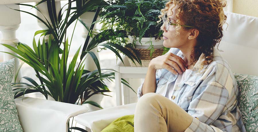 Woman sitting on a couch looking out the window. Perhaps pondering exit taxes when renouncing us citizenship
